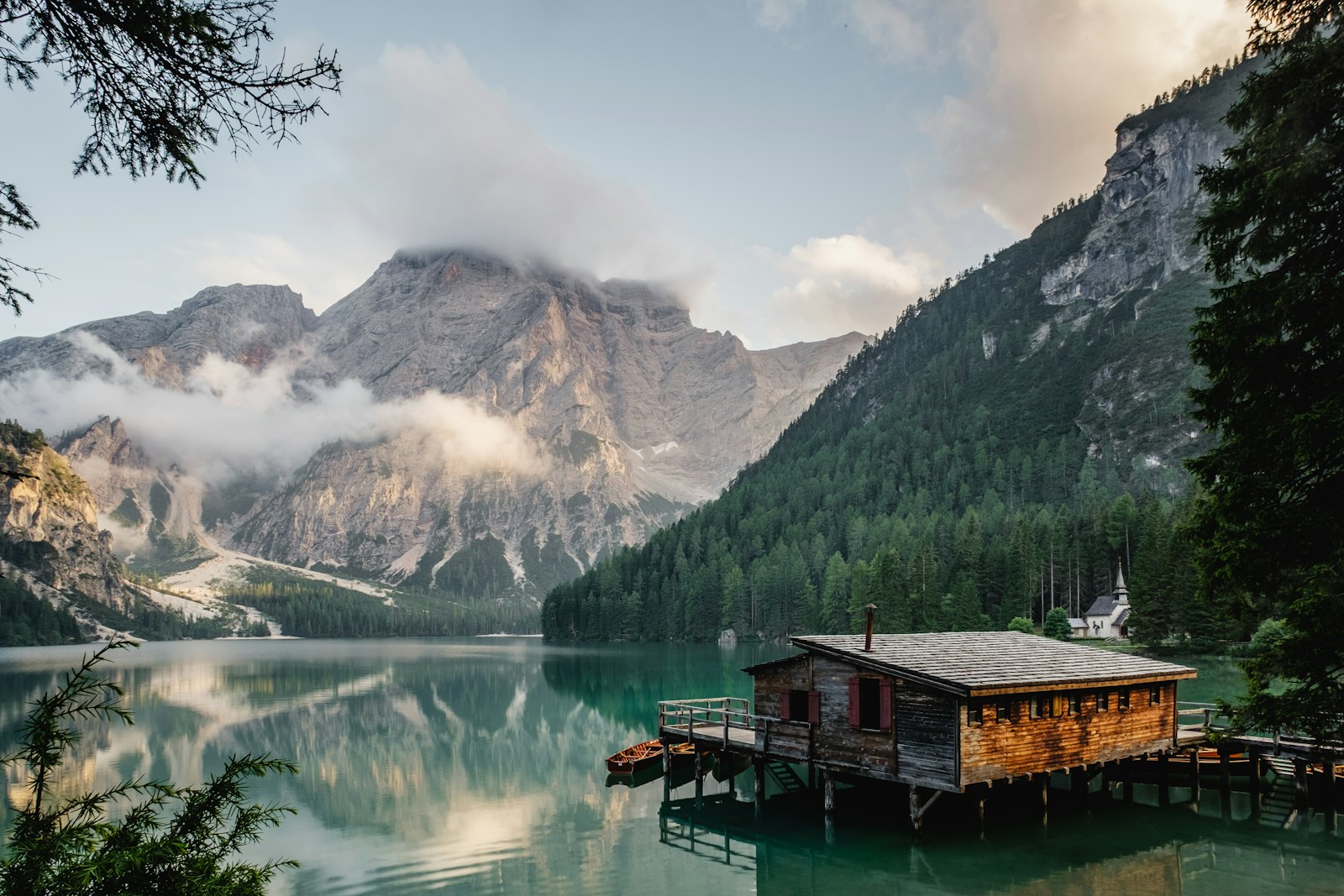 Still alpine lake surrounded by forests and misty mountains